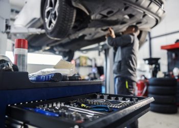 Close up of a tools in a drawer on toolbox with worker repairing car in blurry background at mechanic's shop.
